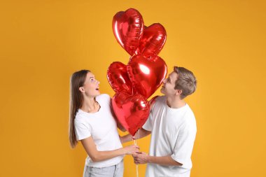 Sarı arka planda kalp şeklinde balonları olan sevimli bir çift. Romantik randevu