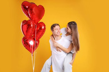 Sarı arka planda kalp şeklinde balonları olan sevimli bir çift. Romantik randevu