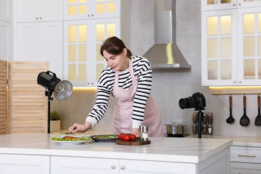 Mutfaktaki masada yemekle kompozisyon oluşturan kadın. Profesyonel yemek fotoğrafçılığı.