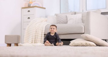 Sevimli küçük bebek evde yerde oturuyor, alçak açılı.