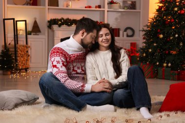 Mutlu çift Noel için dekore edilmiş odada birlikte vakit geçiriyor.
