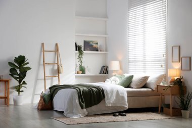 Büyük yataklı, yastıklı, çiçekli ve lambalı şık bir yatak odası. İç tasarım