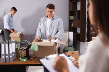 Taşınma günü. Ofisteki kutulara farklı eşyalar koyan bir grup işçi, seçici odaklanma