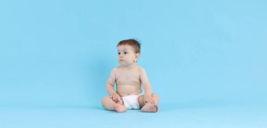 Açık mavi arka planda oturan şirin bir bebek.