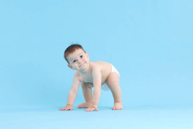 Açık mavi arka planda emekleyen şirin bir bebek.