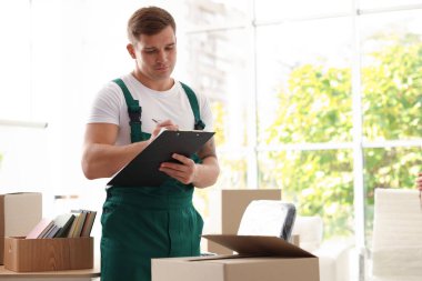 Taşınma günü. Ofiste karton kutuların yanında panosu olan genç bir adam, mesaj için yer var.