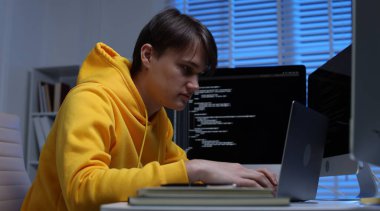 Ofisteki beyaz masada dizüstü bilgisayarda çalışan programcı