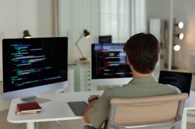 Ofisteki beyaz masada bilgisayar ve dizüstü bilgisayar üzerinde çalışan programcı, arka görünüm