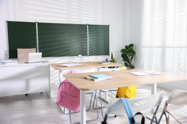 Sınıfta yeşil karatahta, sıralar ve sandalyeler.