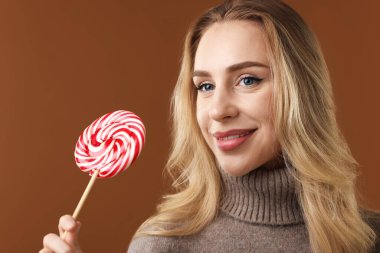 Noel kutlaması. Kahverengi arka planda lolipopu olan kadın.