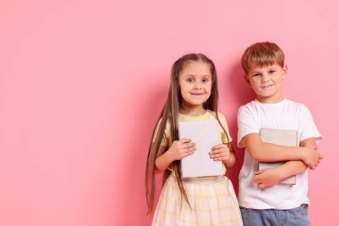 Pembe arka plan kitapları olan sevimli küçük çocuklar, mesaj için yer.