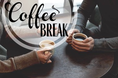 Meslektaşlar kafedeki ahşap masada kahve molası veriyor.