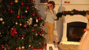 Evde Noel ağacı süsleyen sevimli çocuklar.