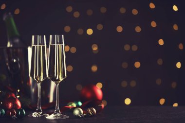 Masadaki bulanık ışıklara karşı köpüklü şarap ve Noel topları. Kutlama kartı