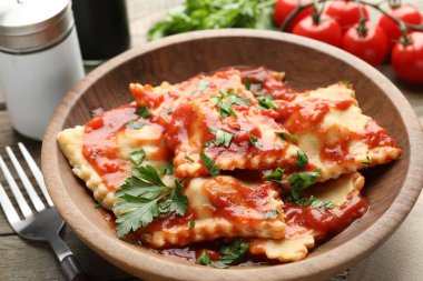 Ahşap masada servis edilen domates soslu ve maydanozlu lezzetli ravioli.