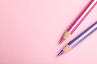 Pembe arka planda farklı göz kalemleri, düz yatış. Metin için boşluk