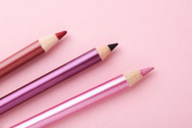 Pembe arka planda farklı göz kalemleri, düz yatış.