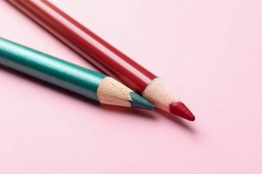 Pembe arka planda parlak göz kalemleri, yakın plan. Metin için boşluk