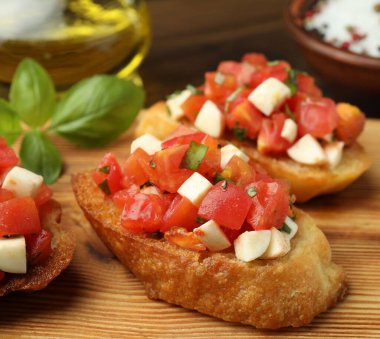 Domatesli lezzetli bruschettalar, mozzarella peyniri ve fesleğen masada servis edilir, yakın plan.