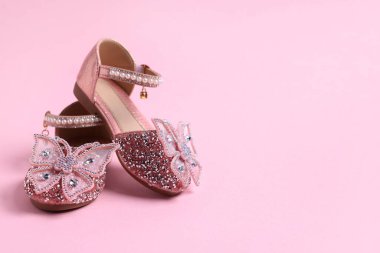 Pembe arka planda bir çift şık çocuk ayakkabısı, yakın plan. Metin için boşluk
