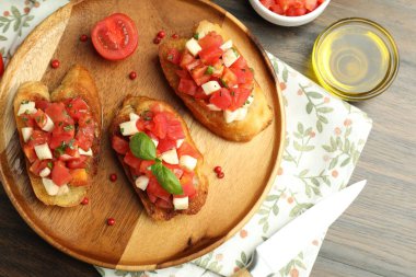 Domatesli lezzetli bruschettalar, mozzarella peyniri ve fesleğen ahşap masada servis edilir.