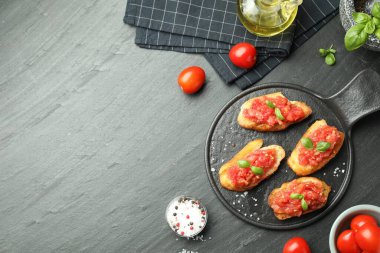 Siyah masada servis edilen domatesli ve fesleğenli lezzetli bruschettalar. Metin için boşluk