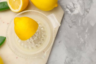 Meyve sıkacağında limon suyu, yapraklar ve açık gri masada taze limonlar. Metin için boşluk