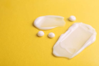 Sarı arka planda nemlendirici krem örnekleri, yakın plan