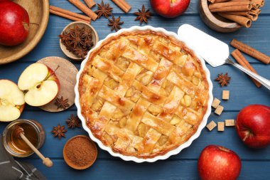 Lezzetli ev yapımı elmalı turta fırın kabında, malzemeler ve spatula mavi ahşap masada, düz yerde.