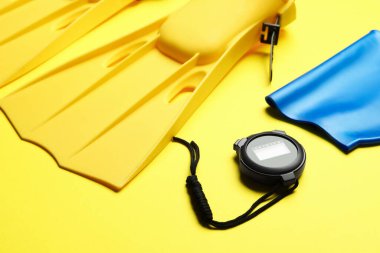 Flippers, dijital kronometre ve sarı arka planda yüzme şapkası, yakın plan