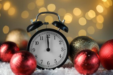 Çalar saat ve suni kar üzerinde parlak mücevherler altın arka planda bulanık ışıklarla, yakın plan. Yeni yıl tebrik kartı.