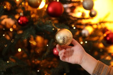 Küçük çocuk Noel ağacını evde süslüyor, yakın plan. Bokeh etkisi