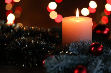 Yakıcı mumlar, köknar ağacı dalları, takılar ve süslemeler siyah arka planda bulanık ışıklarla, yakın plan. Bokeh etkisi