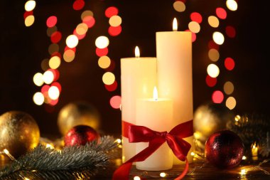 Yakıcı mumlar, köknar ağacı dalları, takılar ve ahşap masa üzerindeki şenlikli ışıklar, bulanık ışıklı siyah arka plan, yakın çekim. Bokeh etkisi