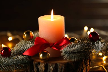 Yanan mum, köknar ağacı dalları ve ahşap masanın üzerinde siyah arka plana karşı takılar, yakın plan. Noel tebrik kartı.