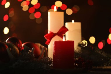 Masada yanan mumlar ve Noel dekoru. Arka planda bulanık ışıklar, yakın plan. Bokeh etkisi