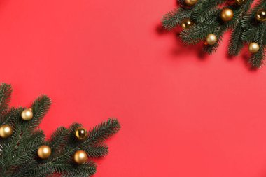 Kırmızı arka planda mücevherleri olan Noel ağacı dalları, düz uzanmış. Metin için boşluk