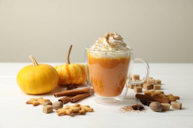 Cam bardakta kremalı balkabaklı latte. Kurabiyeler ve malzemeler beyaz ahşap masada. Yakın plan.