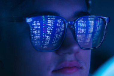 Karanlık arka planda yansıması olan gözlüklü bir adam, yakın plan.