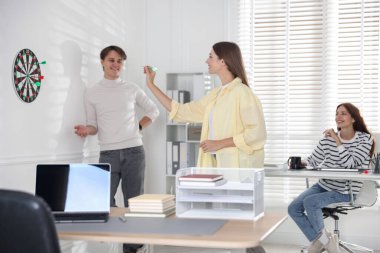 Dart oynayan kadın ve iş arkadaşları ofiste