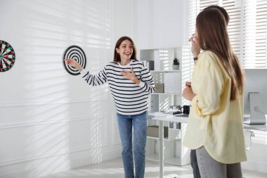 Kadın ve meslektaşları ofiste dart oynuyorlar.