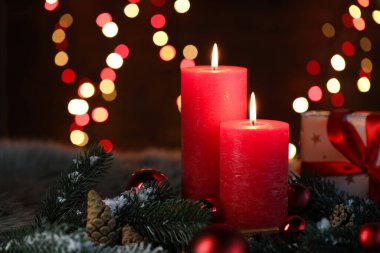 Yakıcı mumlar, köknar ağacı dalları, külahlar ve siyah arkaplan karşısında bulanık ışıklar, yazı için yer ile yakın çekim. Noel tebrik kartı.