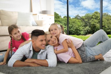 Mutlu aile, büyük pencereli oturma odasında birlikte vakit geçiriyor.