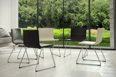 Sandalyeler geniş pencereli odada daireler çiziyor. Psikoterapi seansı