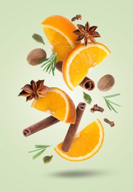 Açık yeşil arka plana düşen sıcak şarap için portakal dilimleri ve baharatlar. Geleneksel Noel içkisi