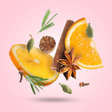 Sıcak şarap malzemeleri: pembe zemine düşen portakal dilimleri ve baharatlar. Geleneksel Noel içkisi