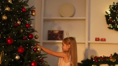Evde Noel ağacı süsleyen küçük bir kız. Kamera aşağı iniyor