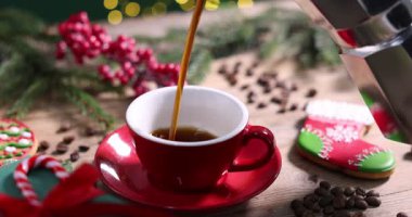 Kadın, ahşap masada fincana aromatik kahve, fasulye ve Noel dekoru dolduruyor. Bokeh etkisi