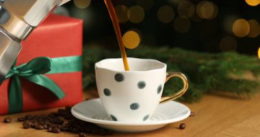 Aromatik kahveyi ahşap masada fincana dökerek siyah arka planda yanıp sönen ışıklar, yakın plan