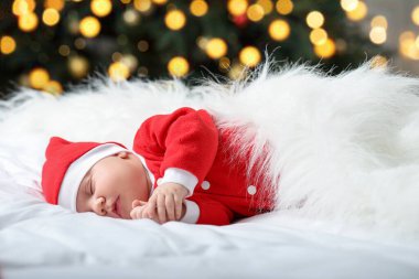 Noel kostümlü şirin bir bebek evde yatakta uyuyor. Bokeh etkisi